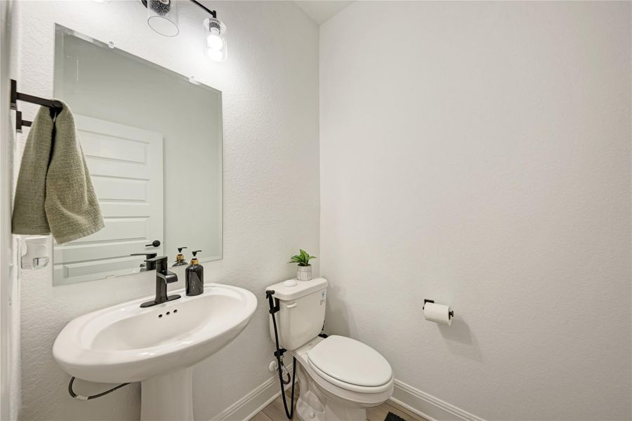 Pedestal sink with matte black faucet, rectangular mirror, and vanity light fixture