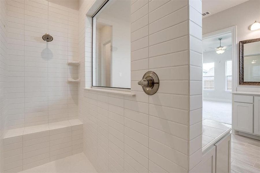 Bathroom featuring a tile shower, vanity, ceiling fan, and hardwood / wood-style flooring