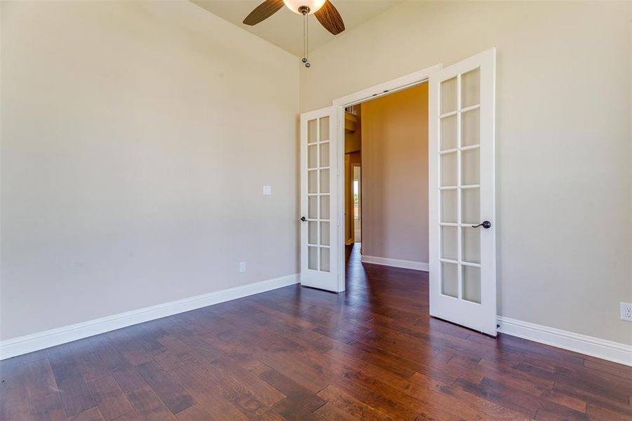 Spare room featuring hardwood / wood-style floors, high vaulted ceiling, french doors, and ceiling fan