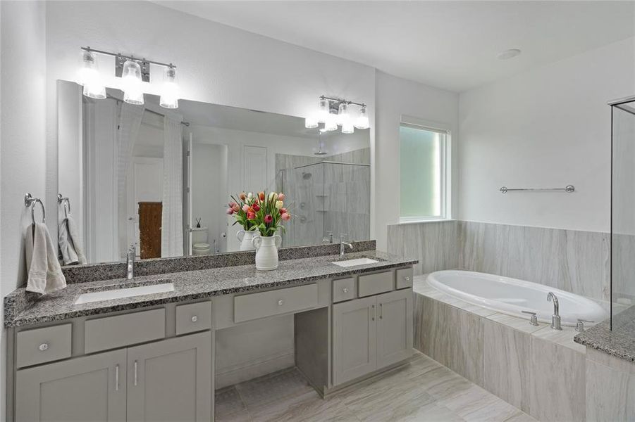 Spacious bathroom featuring a built-in oval soaking tub, large vanity with dual sinks, stone countertops, and tile flooring