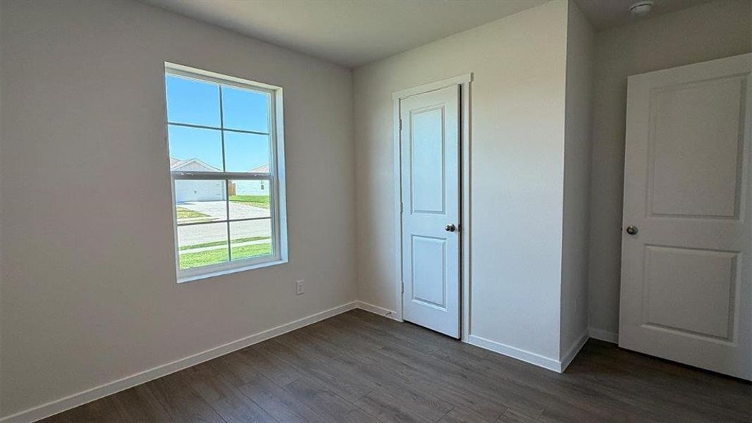 Room featuring wood-finish flooring, a double-pane window, and two paneled doors with chrome hardware Room featuring wood-finish flooring, a double-pane window, and two paneled doors with chrome hardware