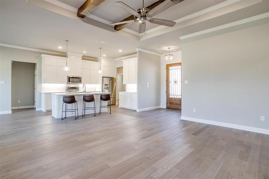 Kitchen with a large island, hanging light fixtures, white cabinetry, and appliances with stainless steel finishes