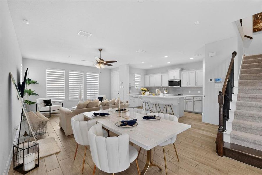 Open concept living area featuring wood-look tile flooring, a dining area, and a kitchen with an island