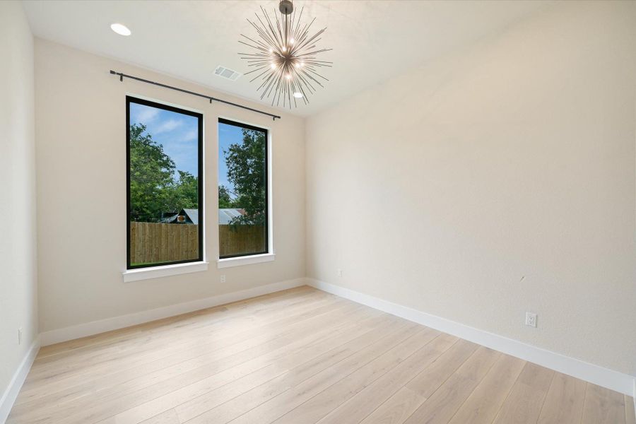 A chic sputnik light fixture illuminates light wood flooring, creating a modern and airy space.