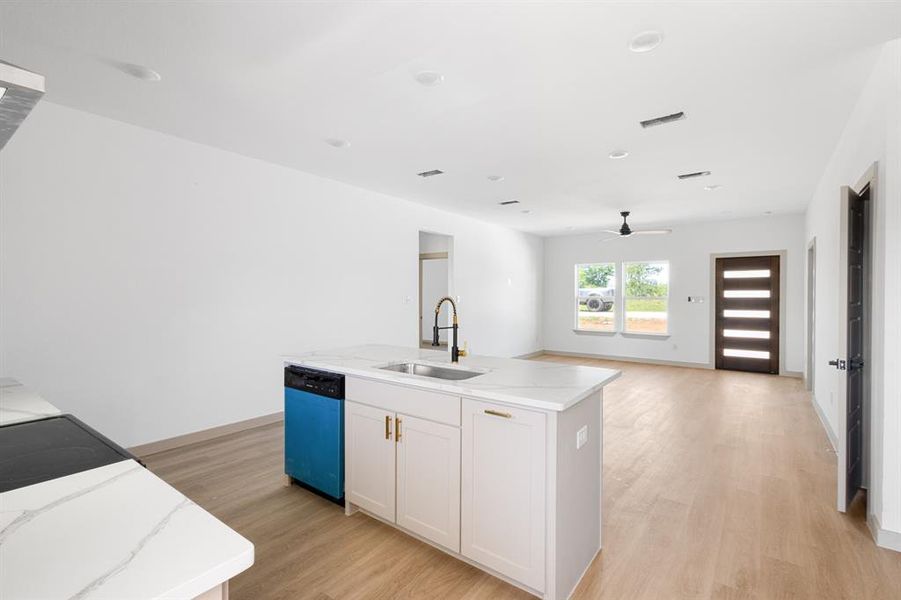 Kitchen with light wood finished floors, dishwasher, a ceiling fan, a sink, and a kitchen island with sink Kitchen with light wood finished floors, dishwasher, a ceiling fan, a sink, and a kitchen island with sink