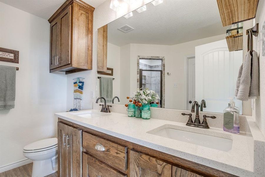 Primary bathroom with a shower stall, double vanity, and light wood-style tile floors Primary bathroom with a shower stall, double vanity, and light wood-style tile floors