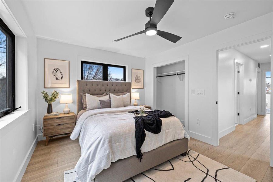 Bedroom with multiple windows, light wood-type flooring, and a closet