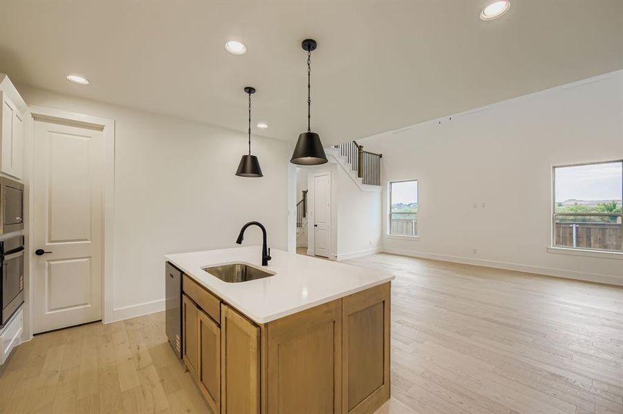 Kitchen with pendant lighting, light wood-type flooring, recessed lighting, an island with sink, and brown cabinets Kitchen with pendant lighting, light wood-type flooring, recessed lighting, an island with sink, and brown cabinets