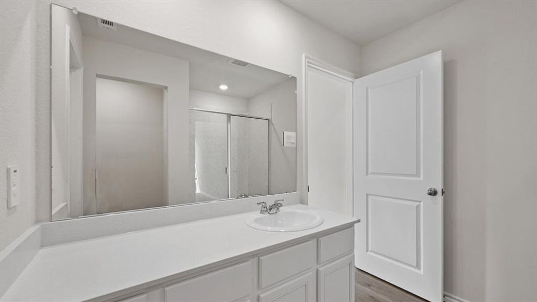 White vanity with a built-in sink, chrome faucet, and expansive wall-mounted mirror