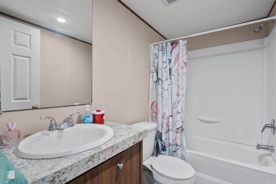 Laminate stone-look counters and a full tub-shower combination complete this functional bathroom.