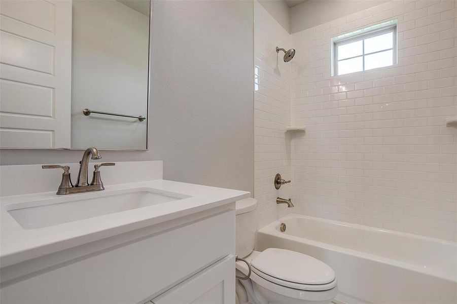 Full bathroom featuring vanity, tiled shower / bath combo, and toilet