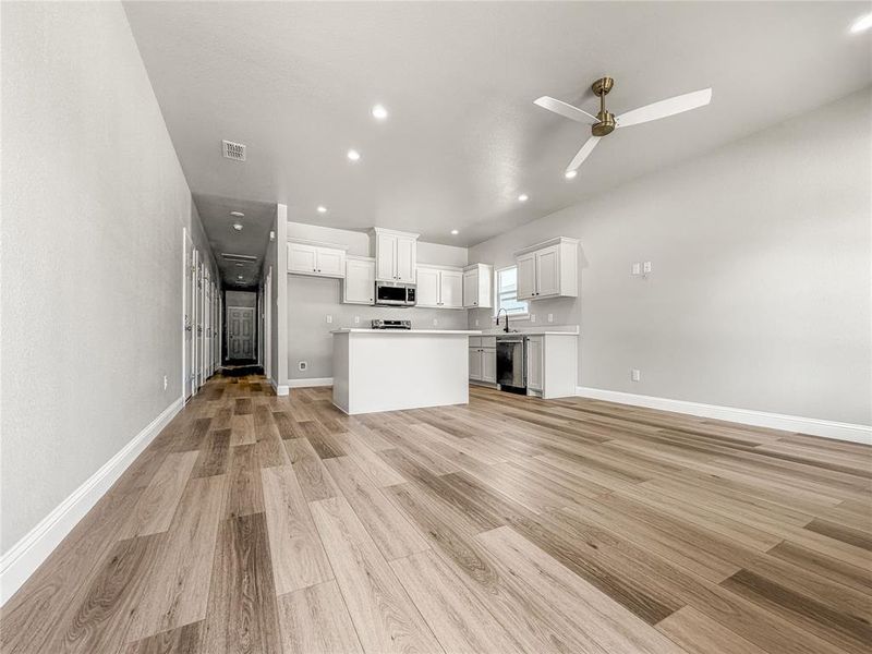 Open-concept living space featuring wood-finish flooring, recessed lighting, and a contemporary ceiling fan Open-concept living space featuring wood-finish flooring, recessed lighting, and a contemporary ceiling fan