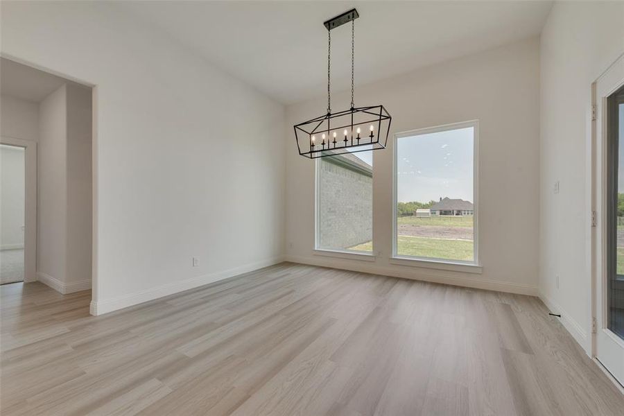 Unfurnished dining area featuring light wood-type flooring and a notable chandelier