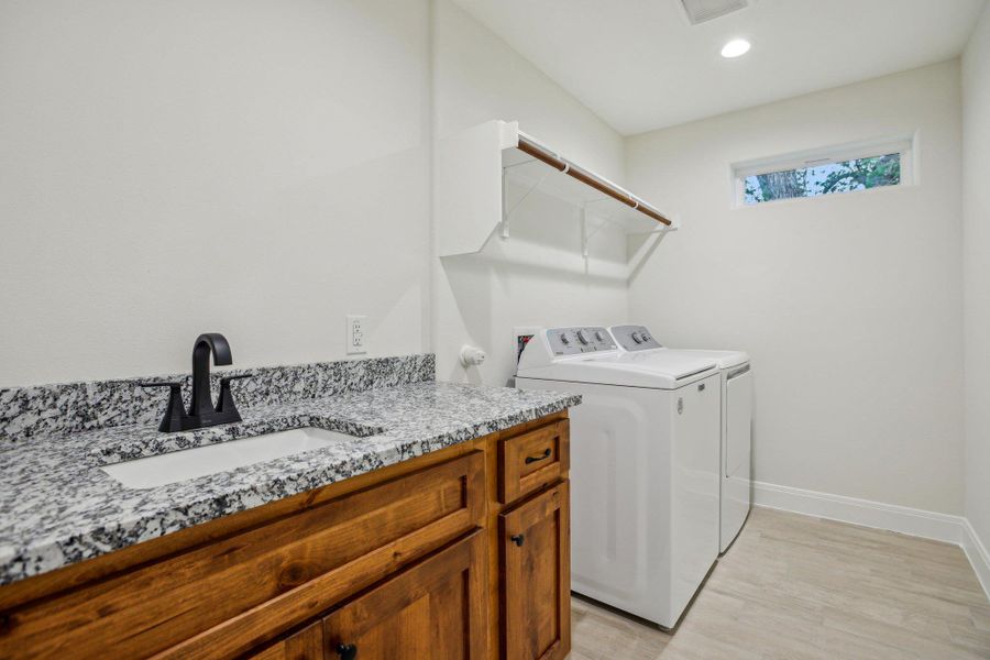 Upstairs Laundry room with a sink, separate washer and dryer, light wood plank tile floors, baseboards, and recessed lighting