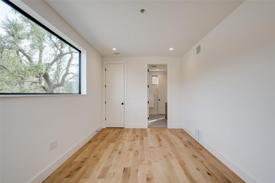 Unfurnished bedroom with light hardwood / wood-style floors, connected bathroom, and a closet