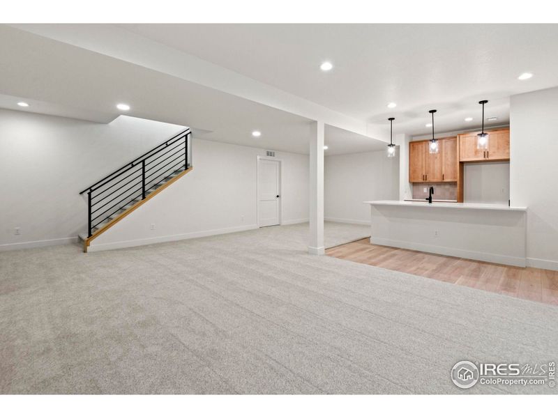 Family room with adjacent game room and wet bar that features continuity with main floor kitchen
