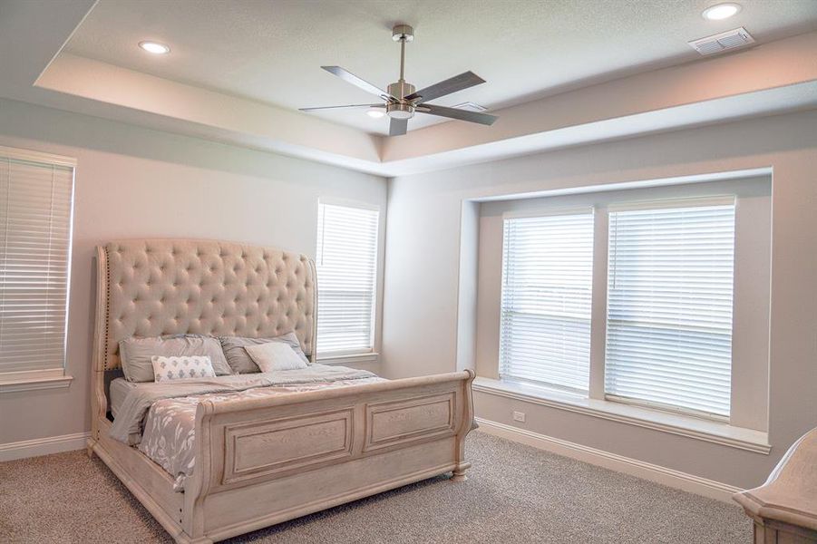 Bedroom with a raised ceiling, recessed lighting, light carpet, and a ceiling fan