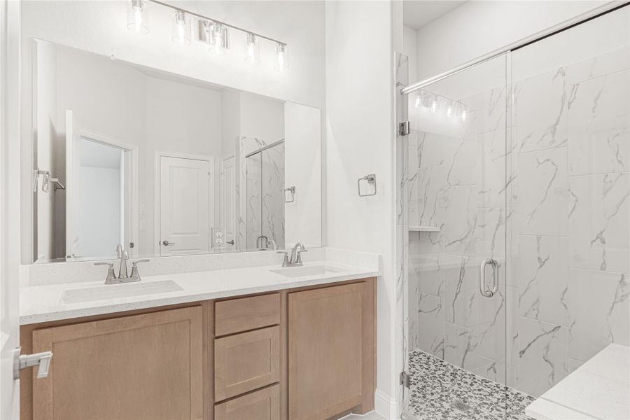 Bathroom with double sink vanity, wood cabinets, and glass walk-in shower with marble tile walls Bathroom with double sink vanity, wood cabinets, and glass walk-in shower with marble tile walls