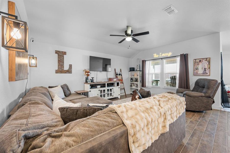 Living area featuring wood finish floors, lofted ceiling, and a ceiling fan Living area featuring wood finish floors, lofted ceiling, and a ceiling fan