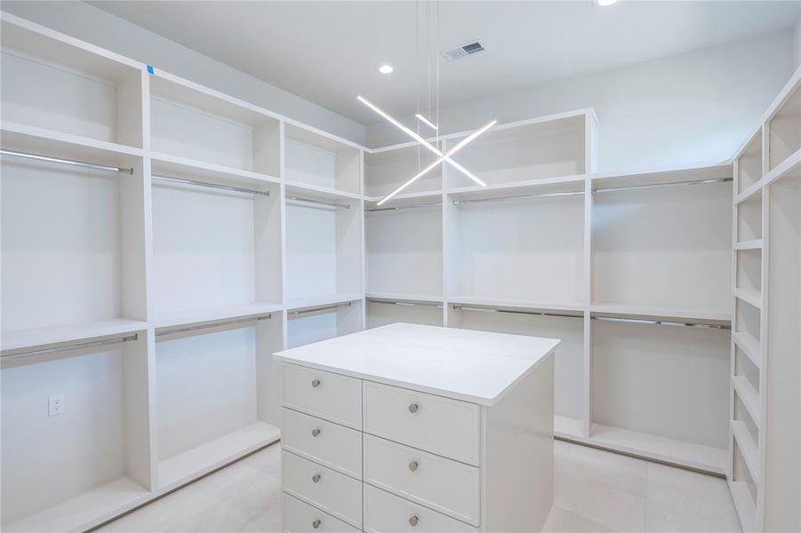 Walk in closet with an inviting chandelier and light tile floors