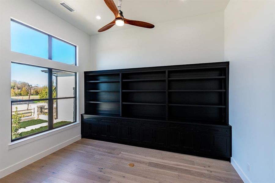 Sustom built-ins with ceiling fan and light wood-type flooring