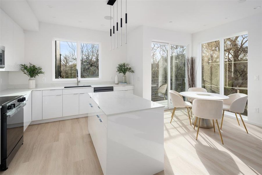 Kitchen with light wood finished floors, white cabinets, a sink, stove, and modern cabinets