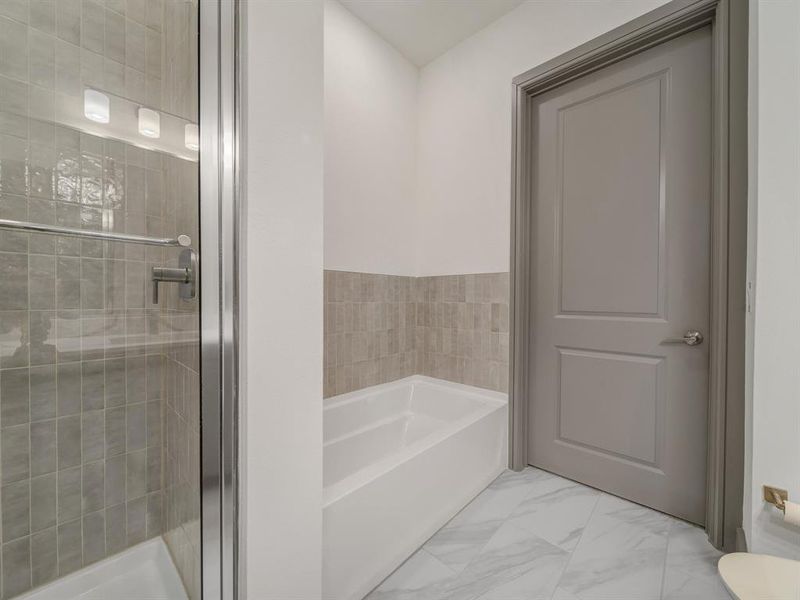 Full bath featuring a garden tub, a shower stall, and light marble finish flooring