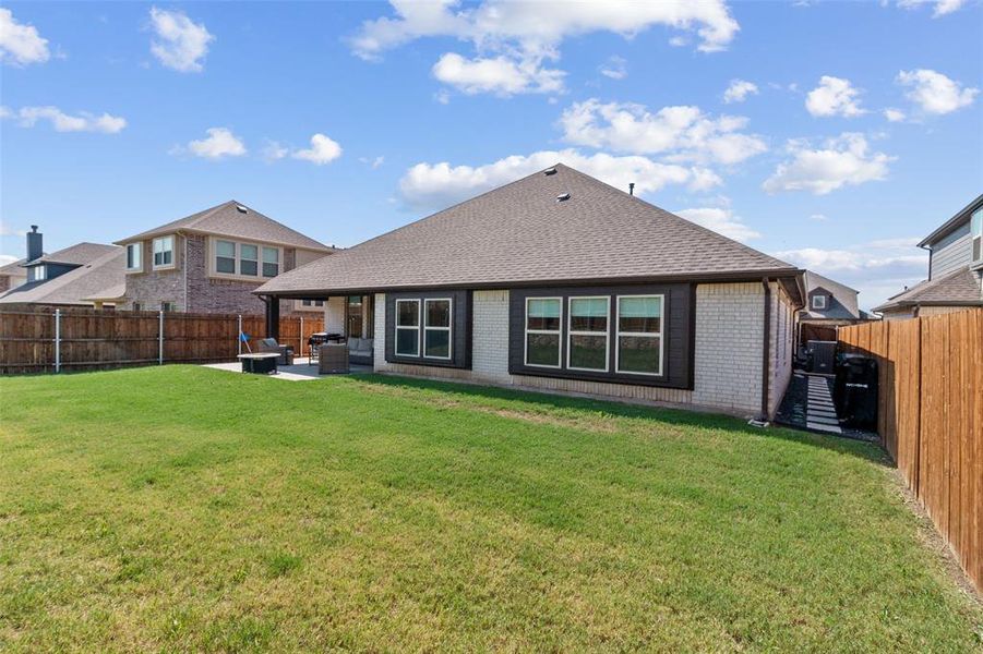 Rear view of property with brick siding, roof with shingles, a patio, a fenced backyard, and an outdoor living space