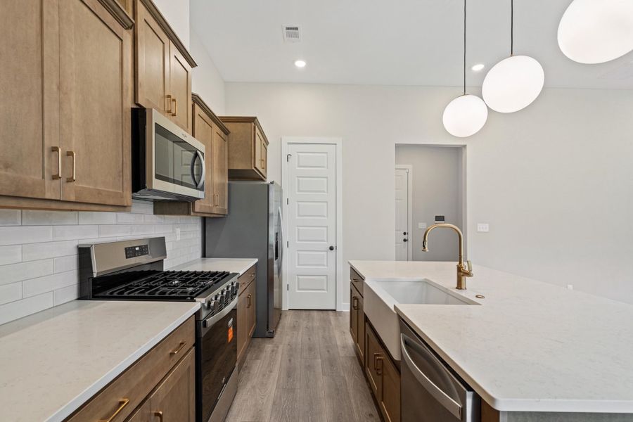 Modern kitchen featuring light wood-finish cabinetry and stainless steel appliances Modern kitchen featuring light wood-finish cabinetry and stainless steel appliances