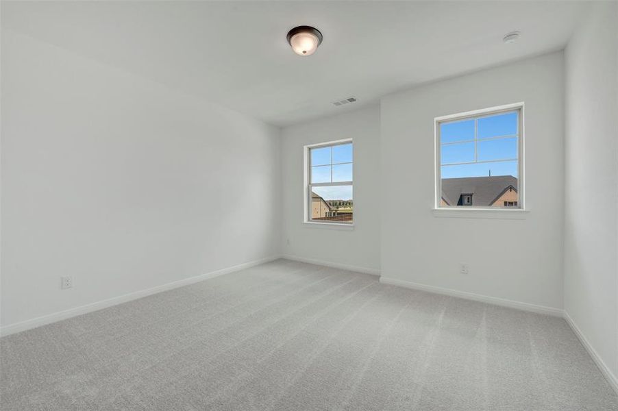 Bright room featuring two windows with white trim, light gray carpet, white walls, and a flush-mount ceiling light fixture Bright room featuring two windows with white trim, light gray carpet, white walls, and a flush-mount ceiling light fixture