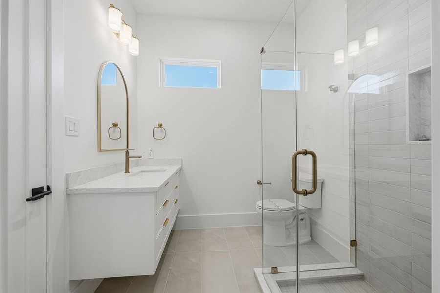 This secondary en-suite bathroom (#2) combines minimalist design with premium materials to offer a comfortable and stylish retreat for guests or family. The space is defined by its crisp white palette and thoughtful architectural details.