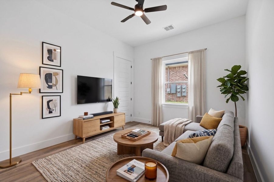 Relax in this inviting living area featuring durable flooring and a refreshing ceiling fan.
