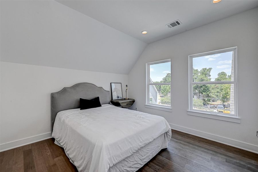 This tranquil guest suite boasts rich wood flooring, vaulted ceilings, and dual windows that overlook the peaceful neighborhood below.