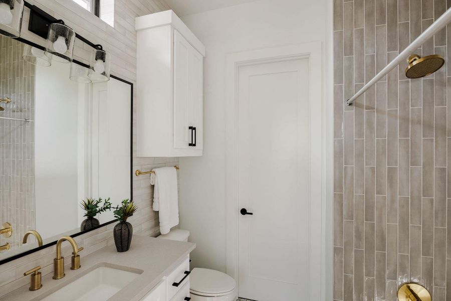 A secondary bathroom features custom cabinetry, stone countertops, and curated tile selections. A secondary bathroom features custom cabinetry, stone countertops, and curated tile selections.