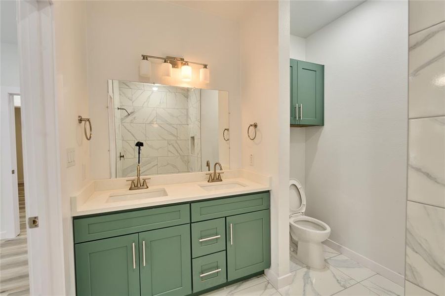 Dual vanity with green cabinetry and white countertops, featuring chrome fixtures and a large mirror