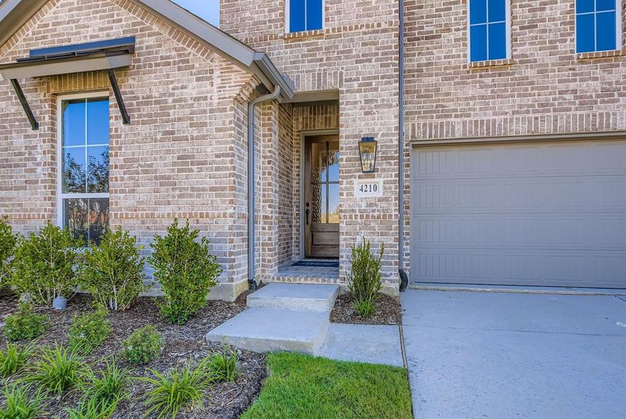Property entrance featuring brick siding and an attached garage Property entrance featuring brick siding and an attached garage