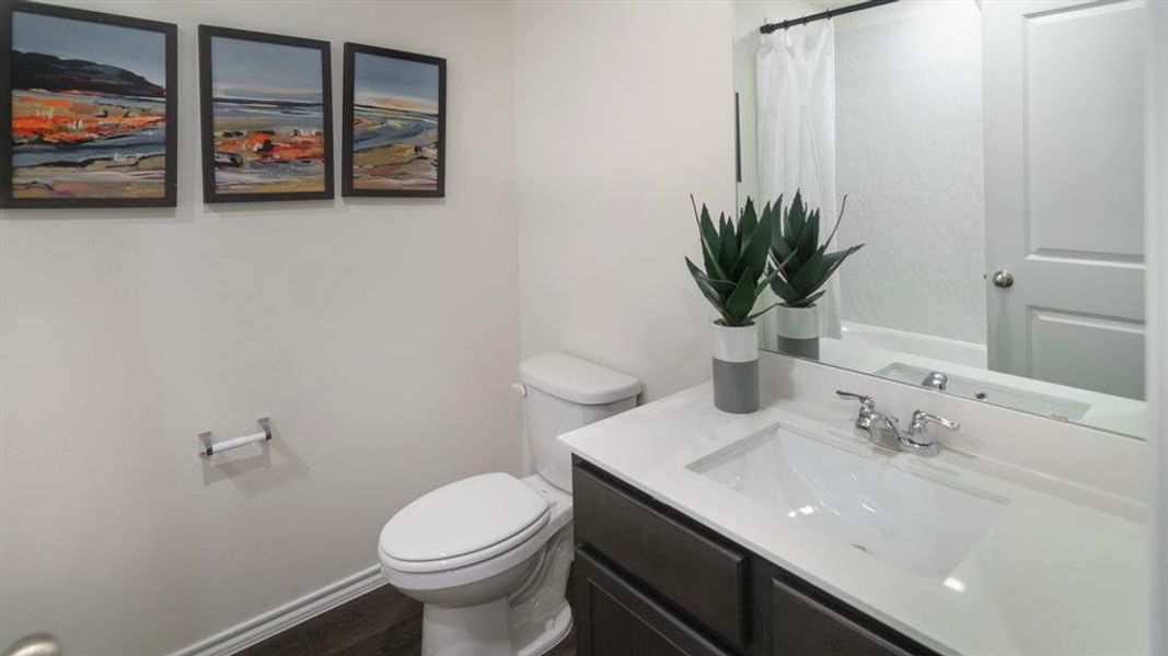 Bathroom featuring a white vanity with an integrated sink, dark wood-finish cabinetry, a chrome faucet, and a large mirror Bathroom featuring a white vanity with an integrated sink, dark wood-finish cabinetry, a chrome faucet, and a large mirror