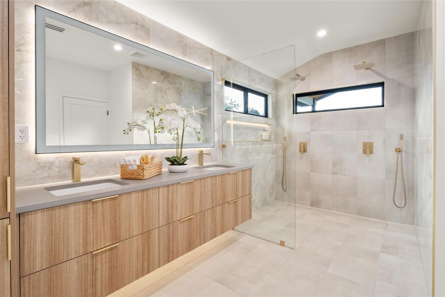 Bathroom featuring tiled shower, double vanity, lofted ceiling, and recessed lighting