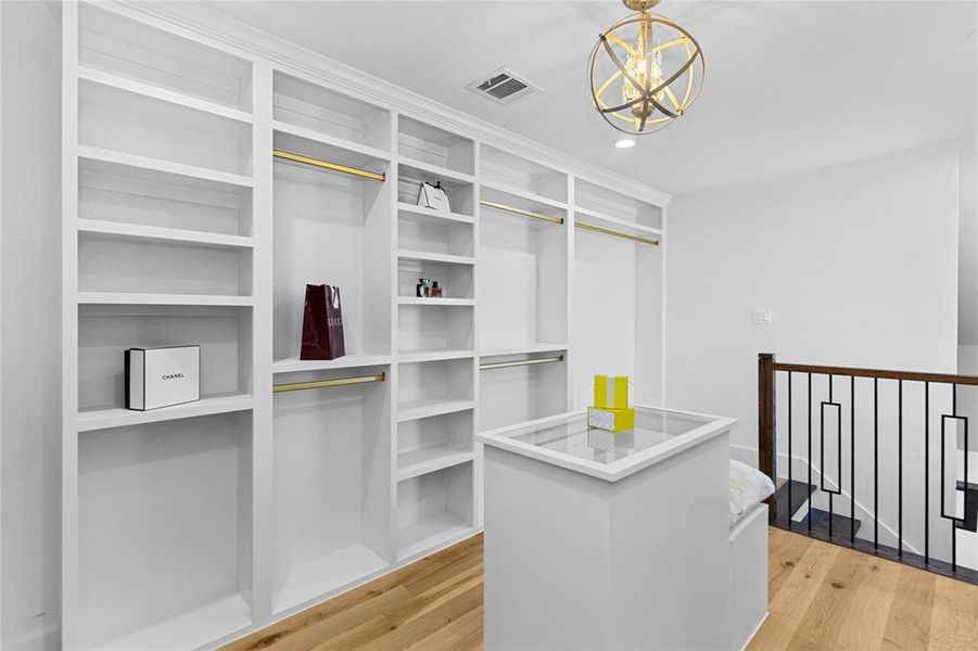 Her Spacious closet featuring light wood finished floors and a chandelier Her Spacious closet featuring light wood finished floors and a chandelier