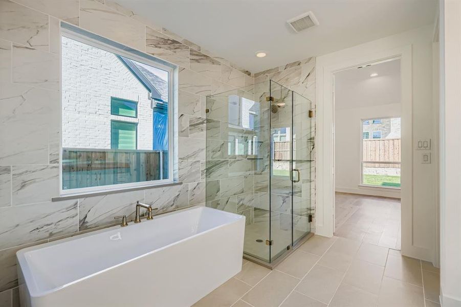 Full bath featuring a freestanding tub, a marble finish shower, light tile patterned floors, tile walls, and recessed lighting Full bath featuring a freestanding tub, a marble finish shower, light tile patterned floors, tile walls, and recessed lighting