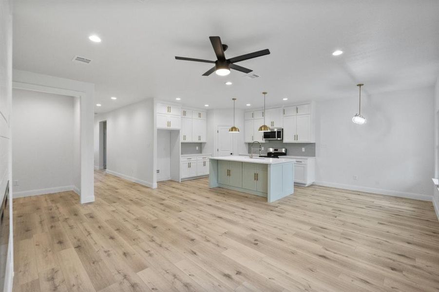 Kitchen with light wood-style flooring, white cabinetry, stainless steel appliances, and light countertops