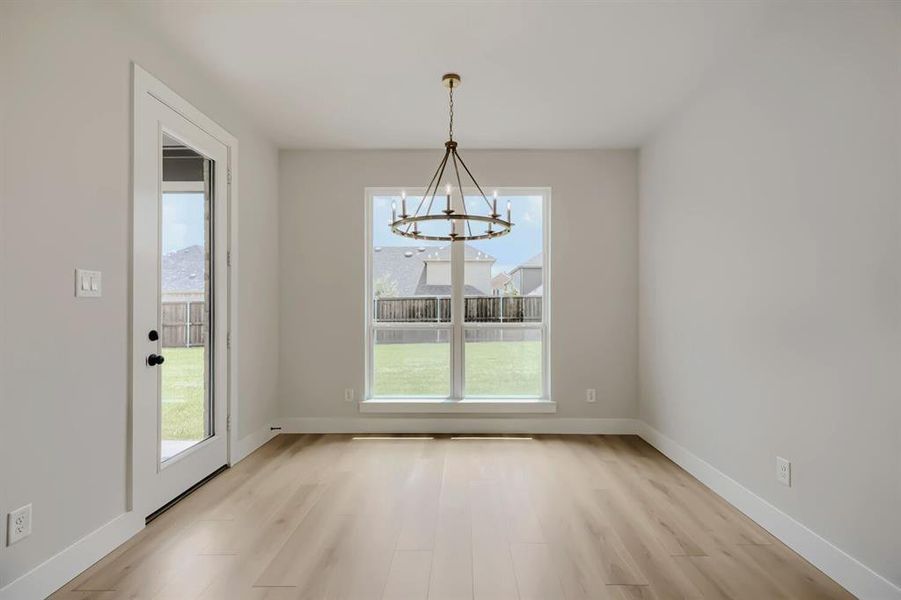 Dining area featuring a contemporary chandelier, wood-finish flooring, and a glass-paned door to the exterior