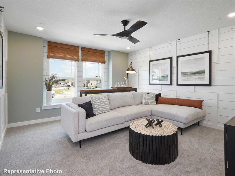 This inviting living space features light gray carpeting, recessed lighting, and a modern ceiling fan