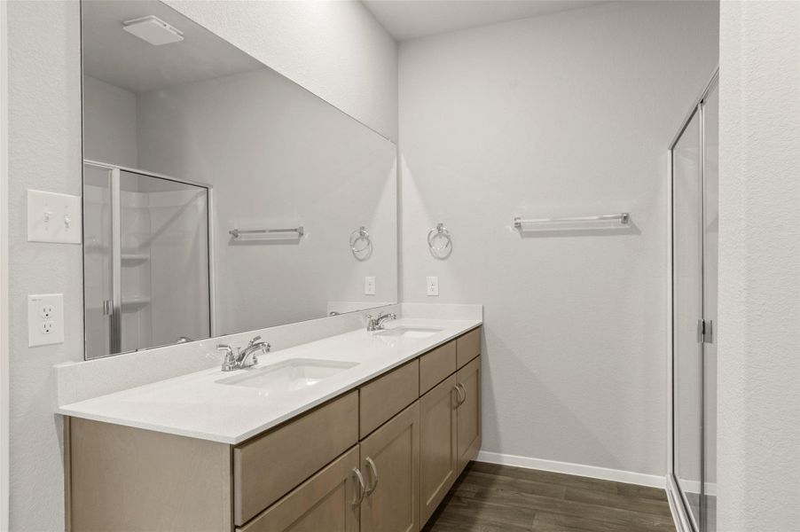 Full bathroom with a shower stall, double vanity, and wood finished floors