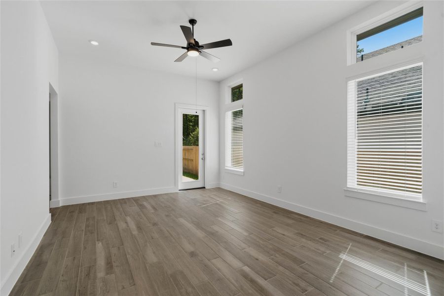 A bright and airy open-concept space featuring tile flooring, high ceilings with recessed lighting and ceiling fan, abundant natural light from large windows (fitted with blinds), and an access door to the back covered patio. A bright and airy open-concept space featuring tile flooring, high ceilings with recessed lighting and ceiling fan, abundant natural light from large windows (fitted with blinds), and an access door to the back covered patio.