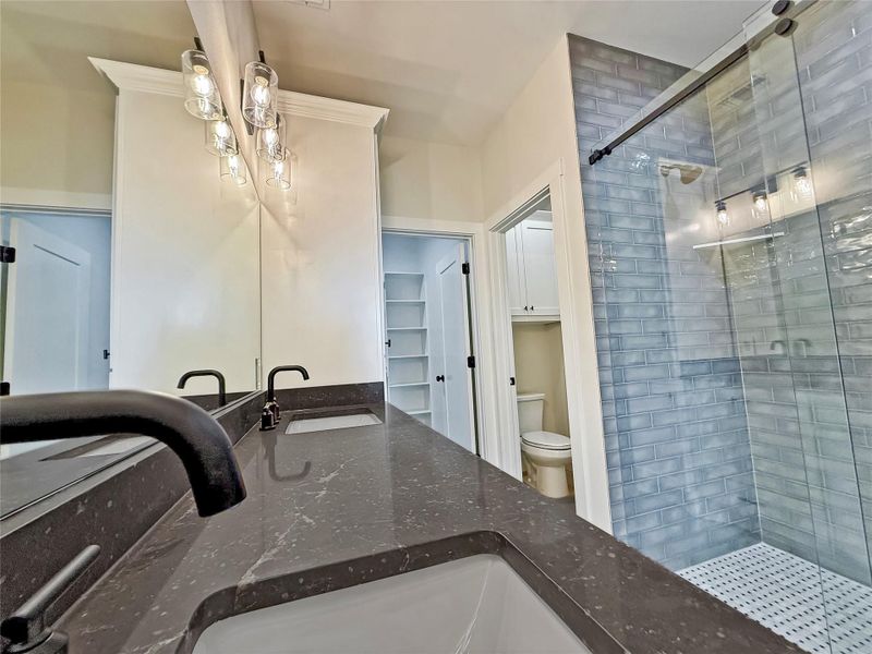 Primary Bathroom featuring a shower stall, vanity, and a closet