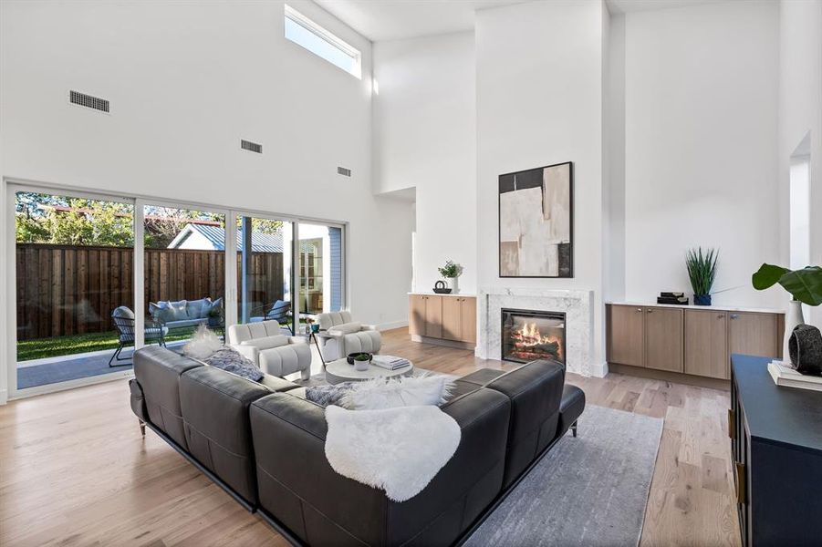 Living room featuring a high end fireplace, plenty of natural light, a high ceiling, and light hardwood / wood-style flooring