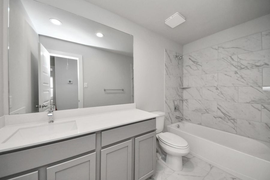 Secondary bath features tile flooring, bath/shower combo with tile surround, light stained wood cabinets, beautiful light countertop. Secondary bath features tile flooring, bath/shower combo with tile surround, light stained wood cabinets, beautiful light countertop.