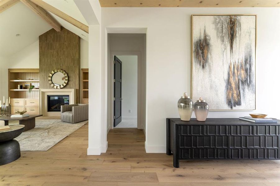 Corridor with beam ceiling, wood finished floors, high vaulted ceiling, and built in shelves Corridor with beam ceiling, wood finished floors, high vaulted ceiling, and built in shelves