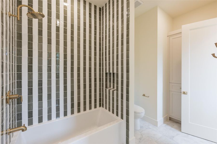 The Jack and Jill bathroom features a bold vertical tile pattern in the shared wet area, paired with brushed gold fixtures for a refined touch. Each side offers private vanities and access, creating a stylish and functional space for shared use. The Jack and Jill bathroom features a bold vertical tile pattern in the shared wet area, paired with brushed gold fixtures for a refined touch. Each side offers private vanities and access, creating a stylish and functional space for shared use.